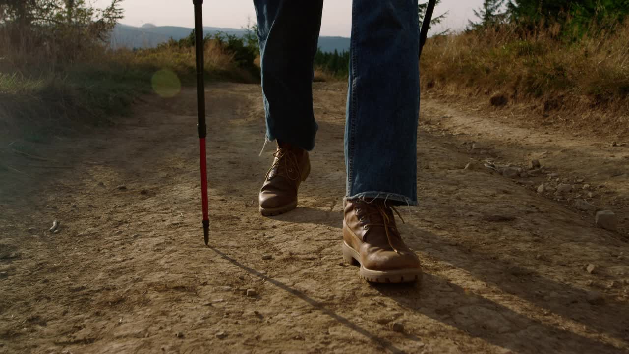 穿着登山靴的男人走在土路上。男性徒步旅行者在山里徒步旅行视频素材