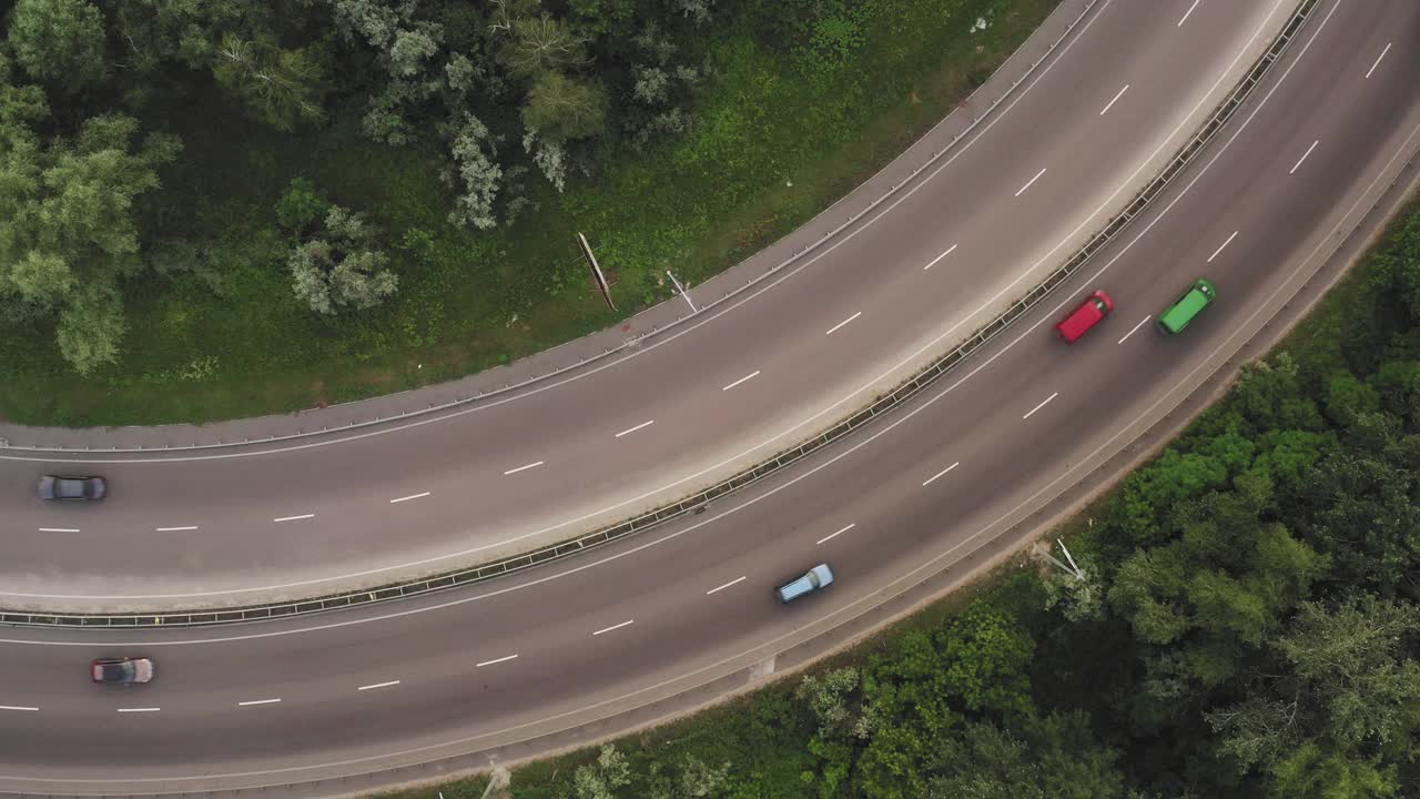 在一段弯曲的道路上的交通在一个延长的俯视图无人机拍摄视频素材