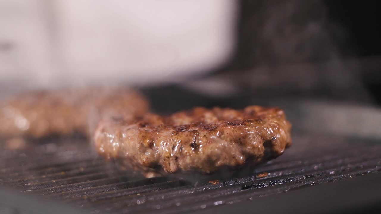 肉汉堡炸肉排在热烤锅上煎。在专业餐厅厨房烹饪食物。准备烧烤晚餐的人。制作美味的汉堡。美味的家现代美食近视频素材