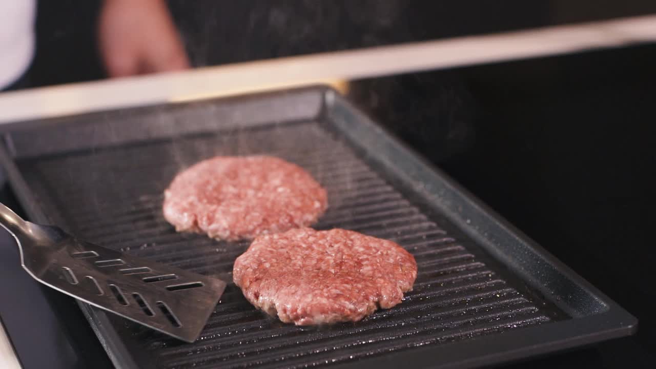 男人在热烤盘上做肉饼。厨师在专业餐厅厨房烹饪食物。准备晚餐的人。制作美味的汉堡。美味的家现代美食近视频素材