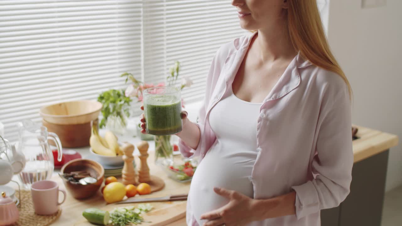 孕妇抚摸肚子和喝冰沙视频素材