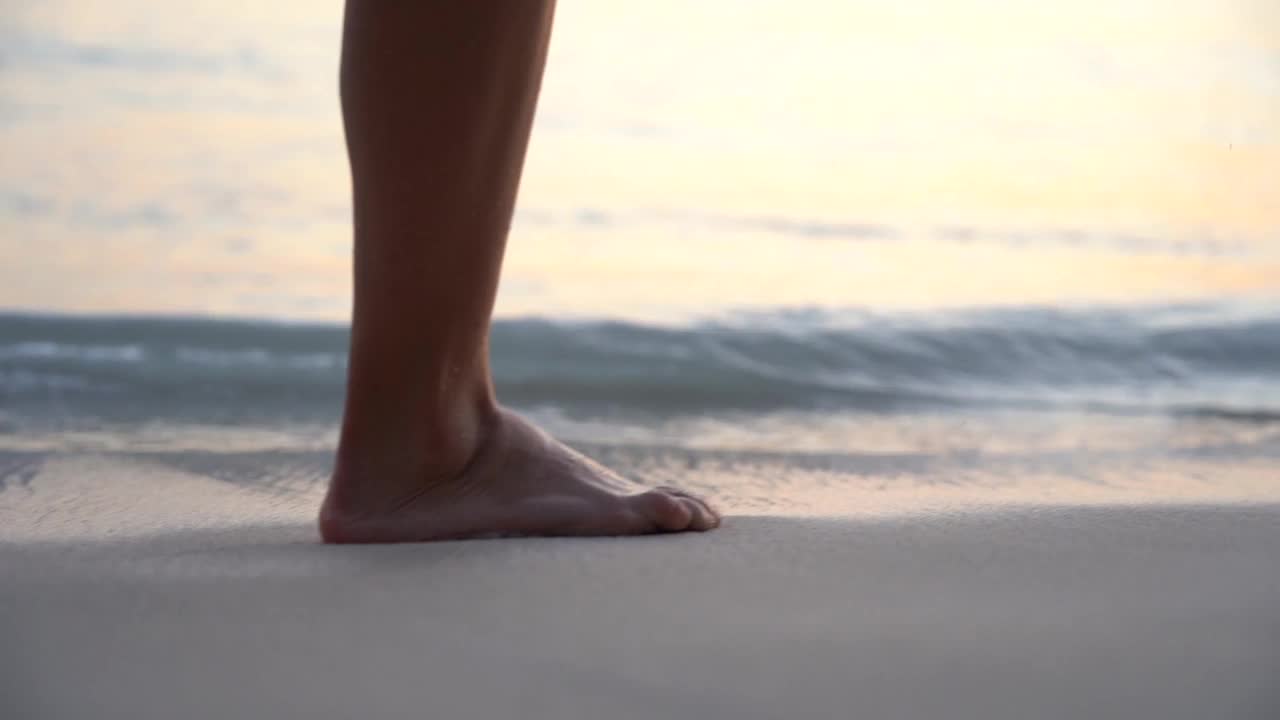 女人的脚在裙子独自走在海滩上在日落的慢镜头。旅游和宁静的概念视频素材