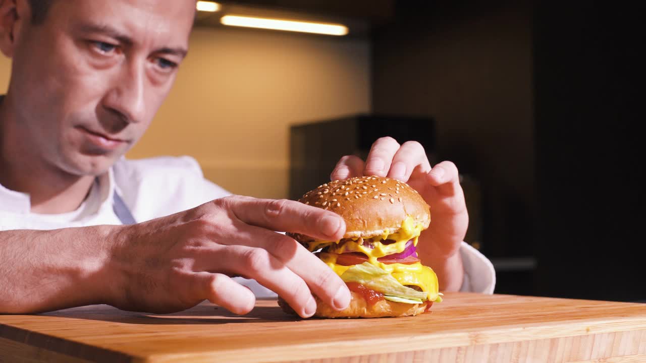 厨师在快餐店厨房准备美味的汉堡。男人在餐厅烹饪食物。在家庭现代厨房里为晚餐制作美味的汉堡包。餐饮服务。视频素材