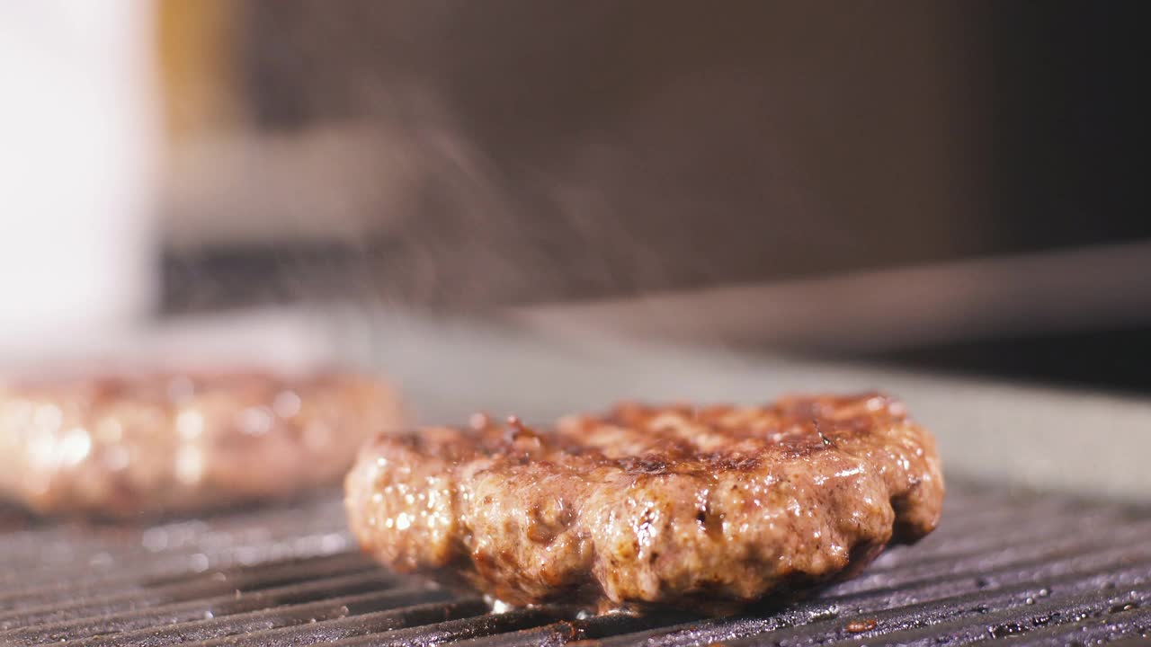 男人把芝士放在肉上，汉堡肉排放在热烤盘上。在专业餐厅厨房烹饪食物。准备晚餐的人。制作美味的汉堡。美味的家现代美食近视频素材