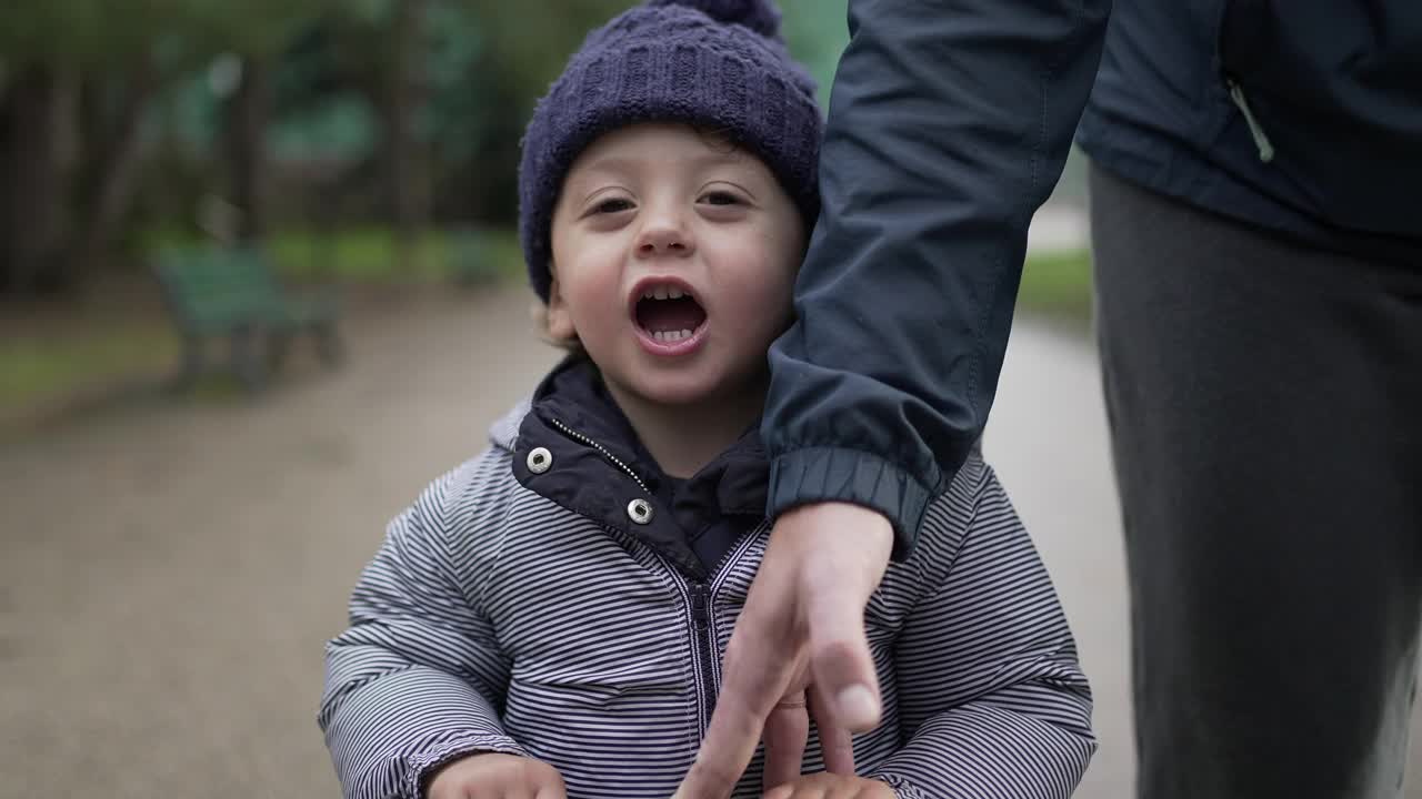 妈妈在操场上帮助蹒跚学步的婴儿骑滑板车视频素材