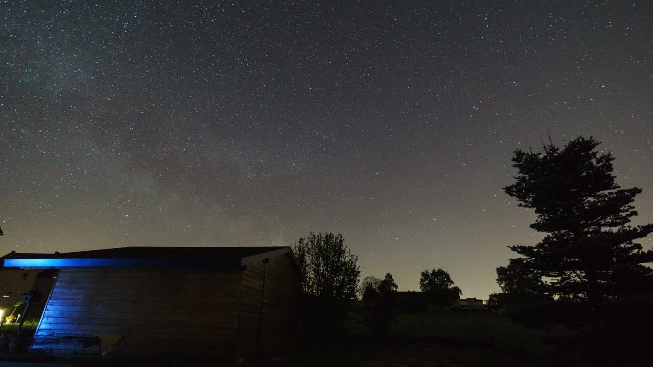 移动的银河作为星星的踪迹在夜空与冷杉和shed在前景视频素材