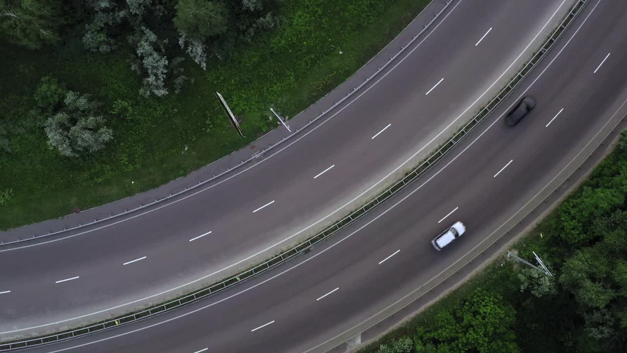 汽车和卡车在绿树丛中沿着高速公路行驶——火箭无人机的射击视频素材