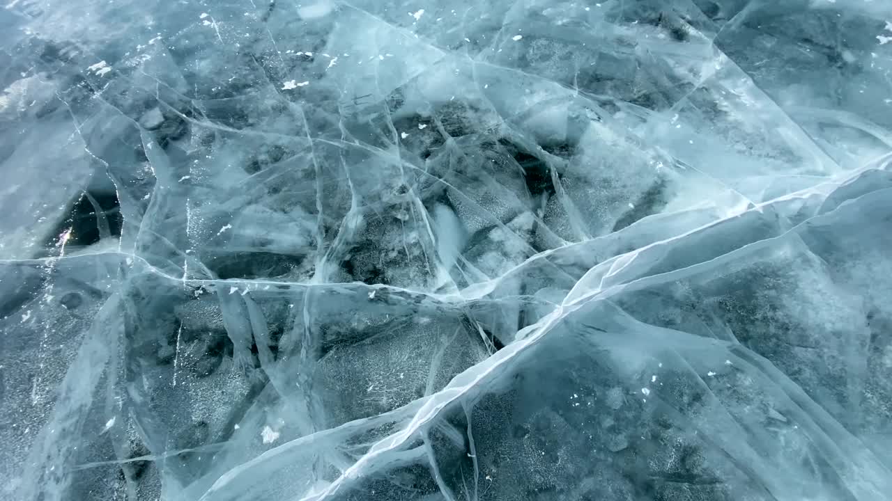 一块冰从高处坠落，在结冰的贝加尔湖光滑透明的蓝色冰上破碎的慢动作视频。视频素材