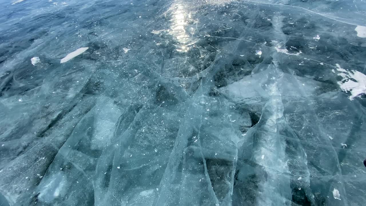 这家伙在结冰的贝加尔湖上打碎了一块光滑透明的蓝色冰。视频素材