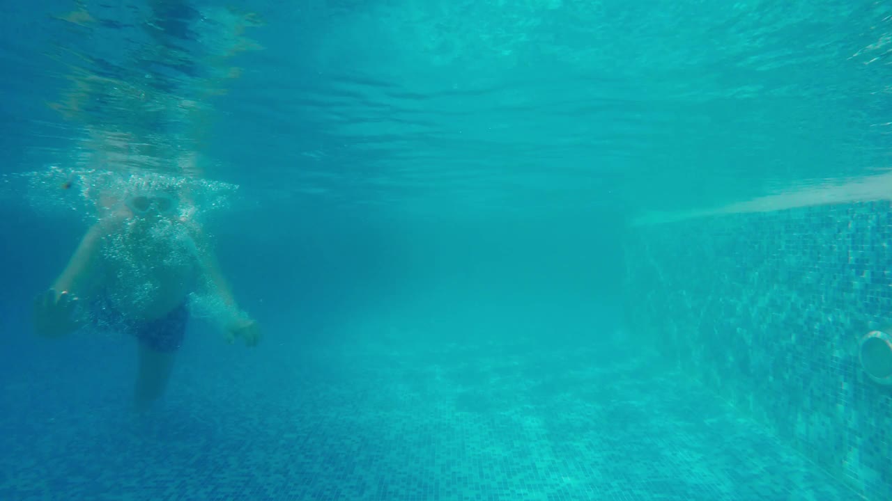 快乐的亚洲男孩在夏天的公共游泳池游泳，在水的视野。视频素材