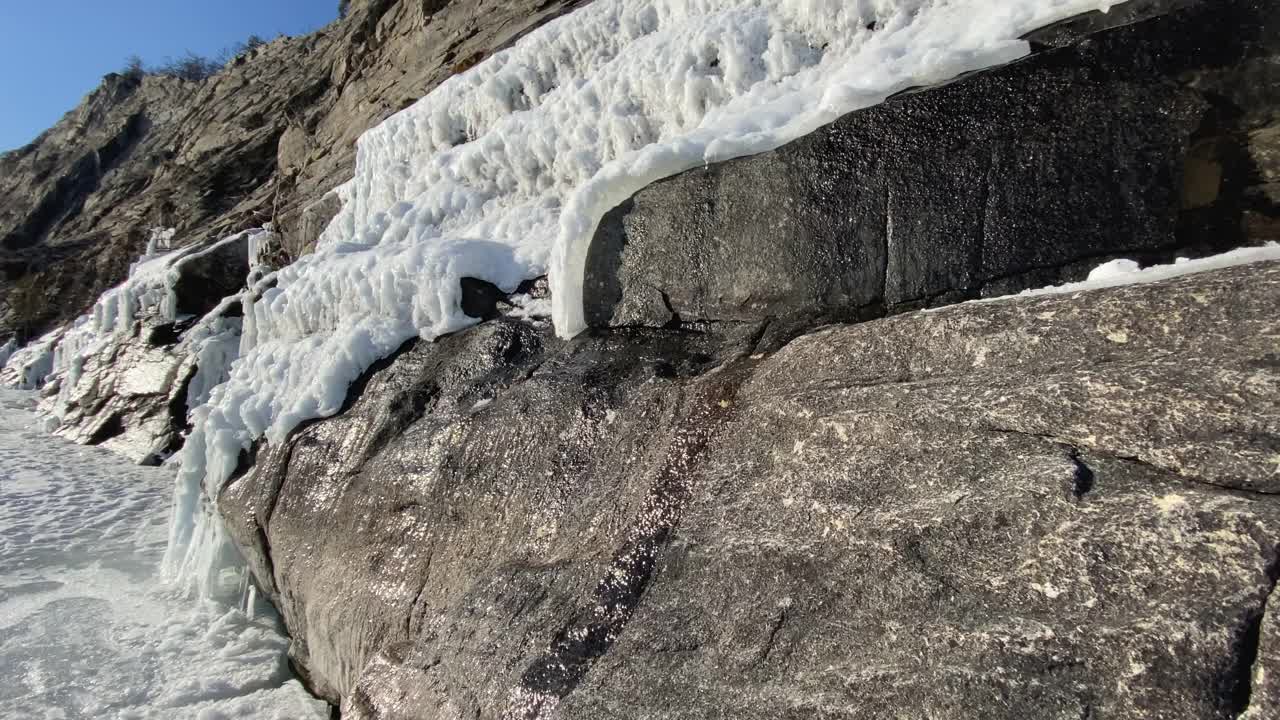 春天在山上。小溪从峭壁上奔流而下。岩石上的雪和冰。视频素材