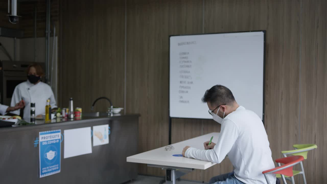 在一所烹饪学校的烹饪课上，同学们用肘部碰撞来打招呼，所有人都戴着防护口罩视频素材