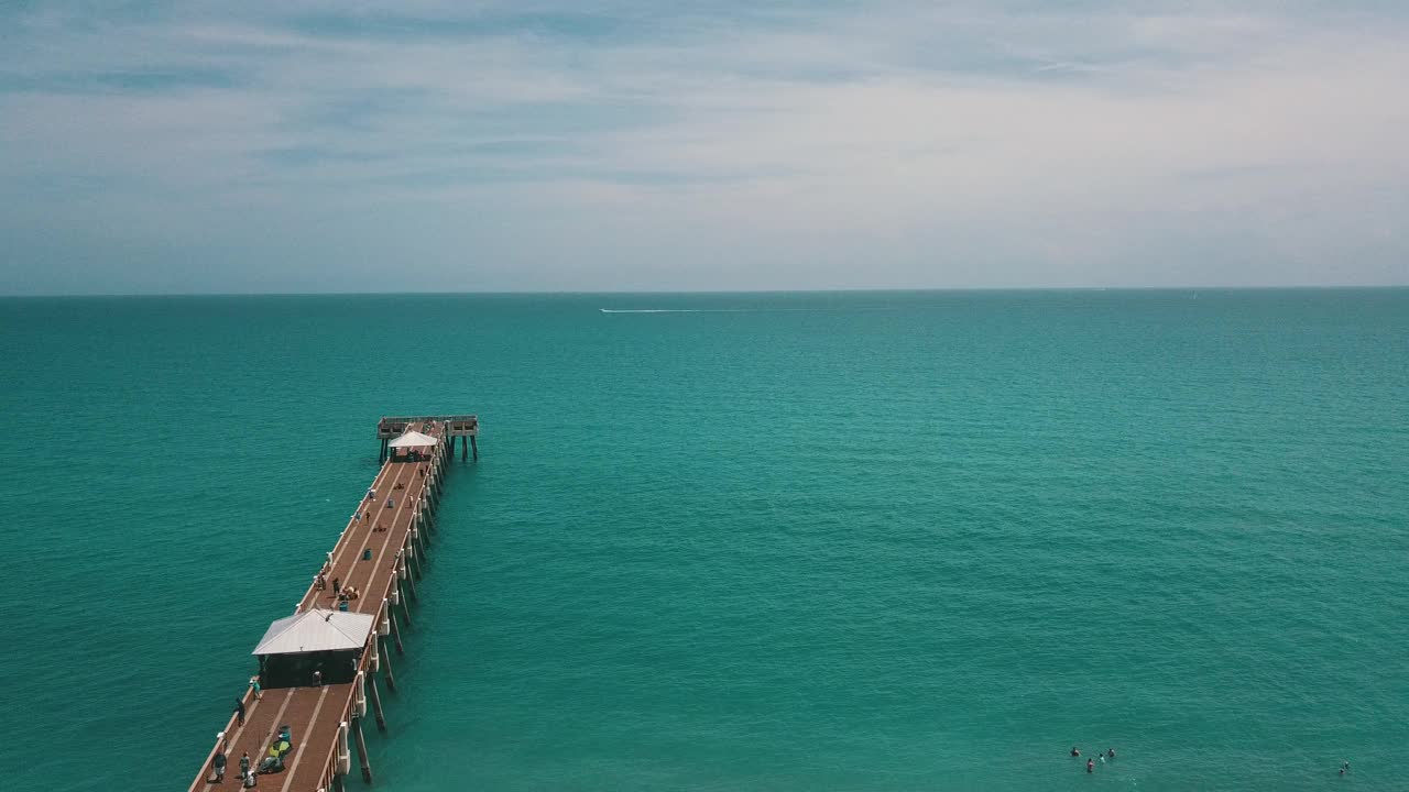 在朱诺海滩码头鸟瞰图，佛罗里达州与明亮的蓝色海水正午在春假期间在2021年3月视频素材