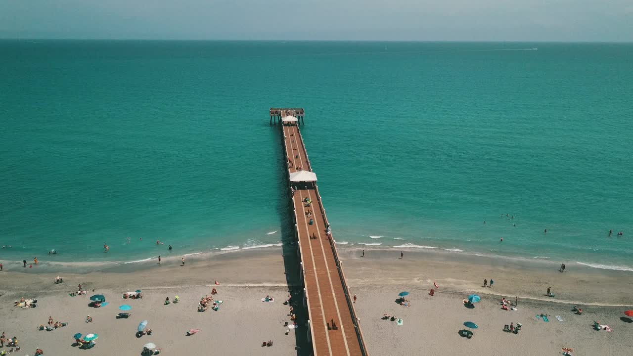 在朱诺海滩码头鸟瞰图，佛罗里达州与明亮的蓝色海水正午在春假期间在2021年3月视频素材