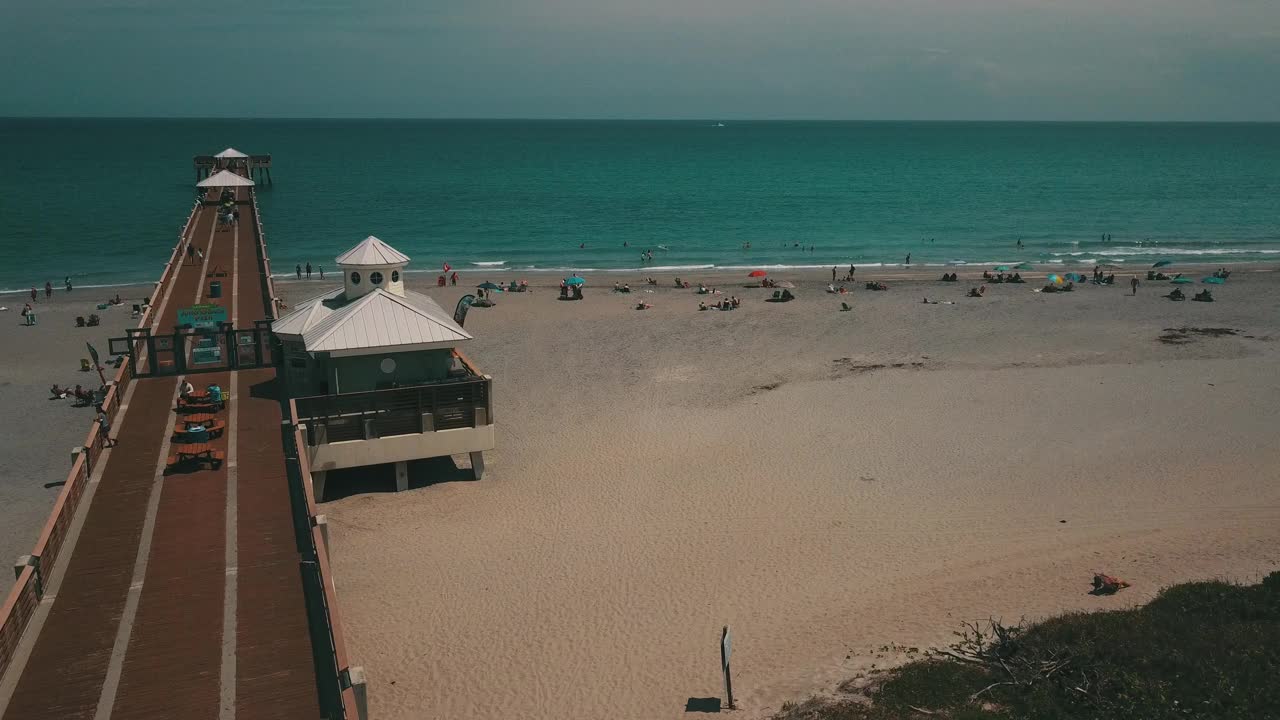 在朱诺海滩码头鸟瞰图，佛罗里达州与明亮的蓝色海水正午在春假期间在2021年3月视频素材