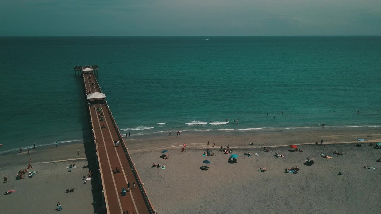 在朱诺海滩码头鸟瞰图，佛罗里达州与明亮的蓝色海水正午在春假期间在2021年3月视频素材