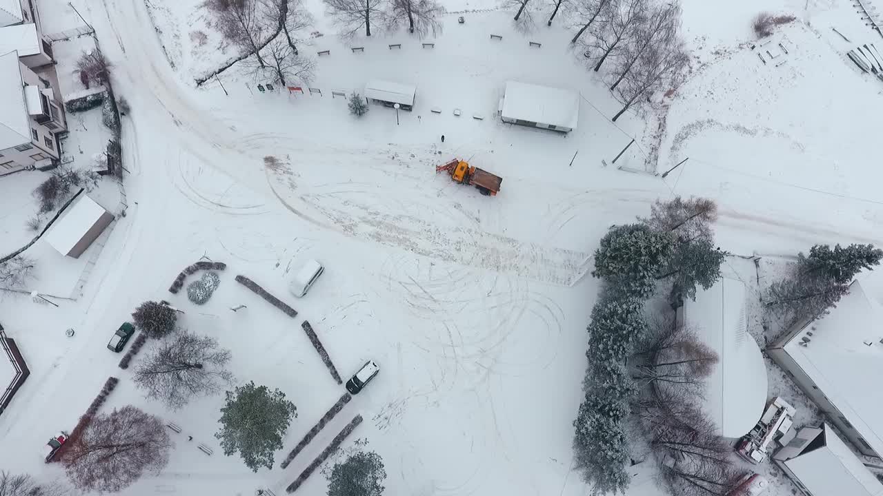 空中拍摄的吹雪机在下雪的街道上。视频下载