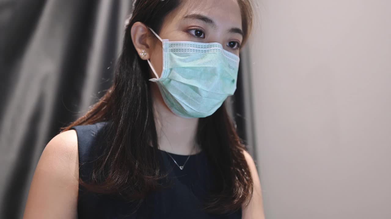 在家里使用笔记本电脑并戴上防护口罩以预防Covid-19病毒的妇女视频素材