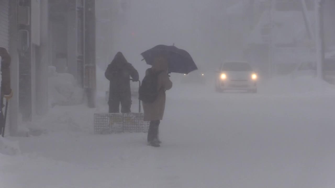 日本山形，在暴风雪中铲雪的人从身边经过视频素材