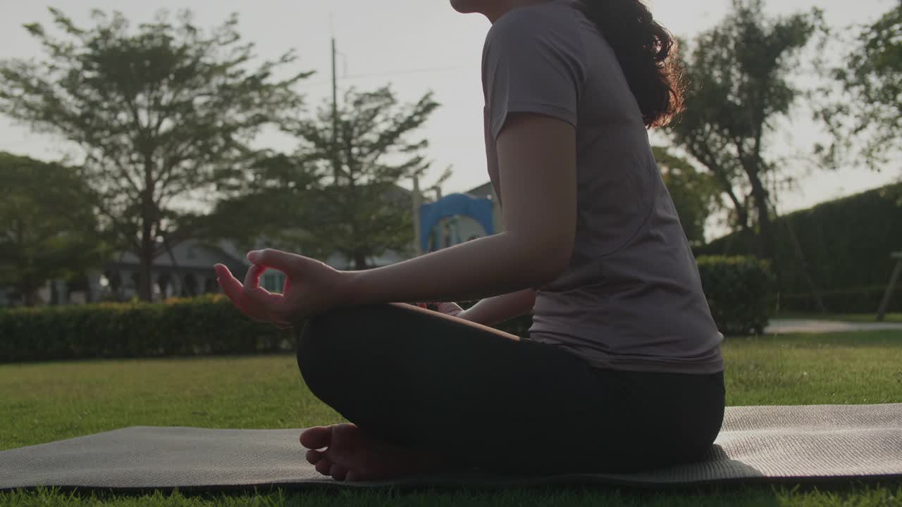 亚洲妇女坐在垫子上莲花的姿势视频素材