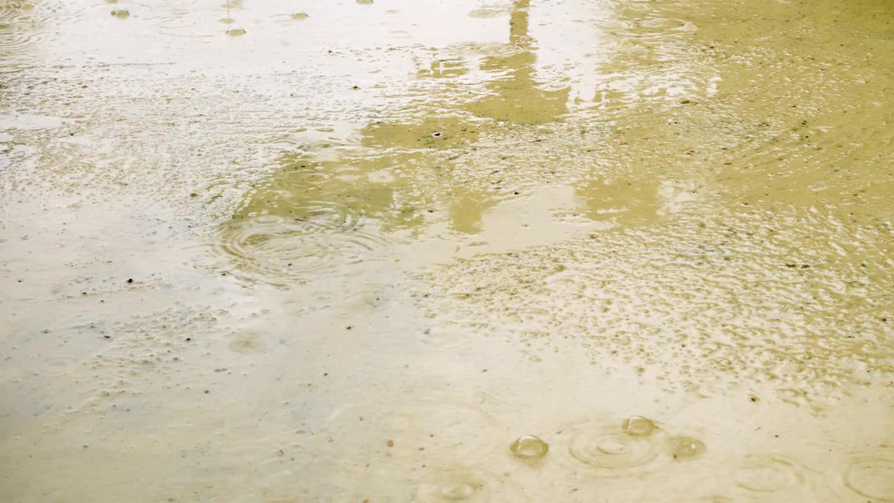 大雨滴落在潮湿的沥青表面的特写。潮湿的水坑和水泡视频素材