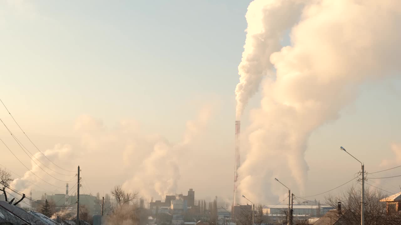 城市上空一家工厂的烟囱冒出浓烟，直冲云霄。化工管道压在城市上空。视频素材