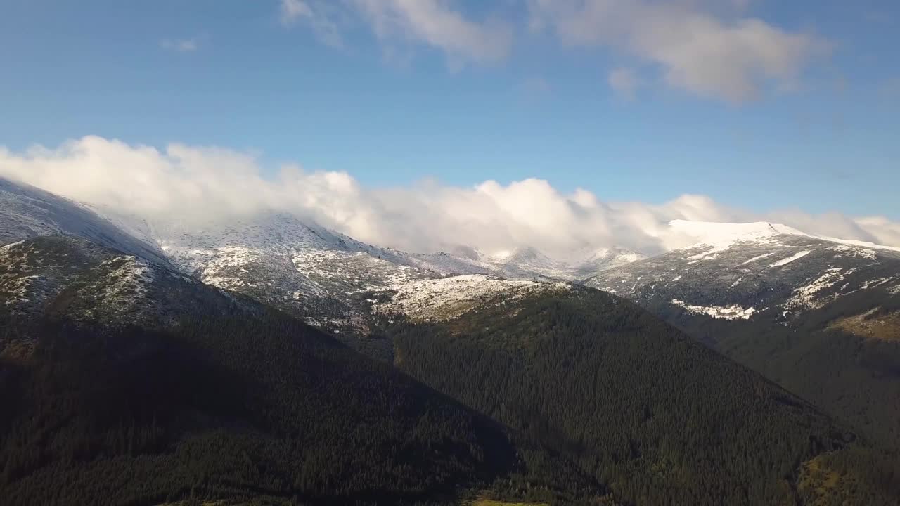 高高的山峰上覆盖着秋天的云杉林，高高的山峰上覆盖着积雪。视频素材