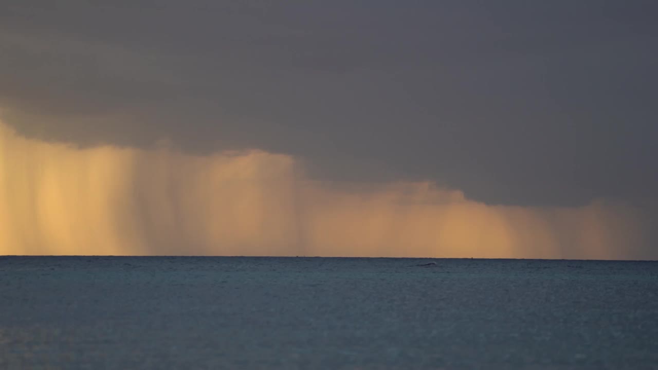 日出时海面上有风暴，呈橙色。水面上有大雨和乌云视频素材