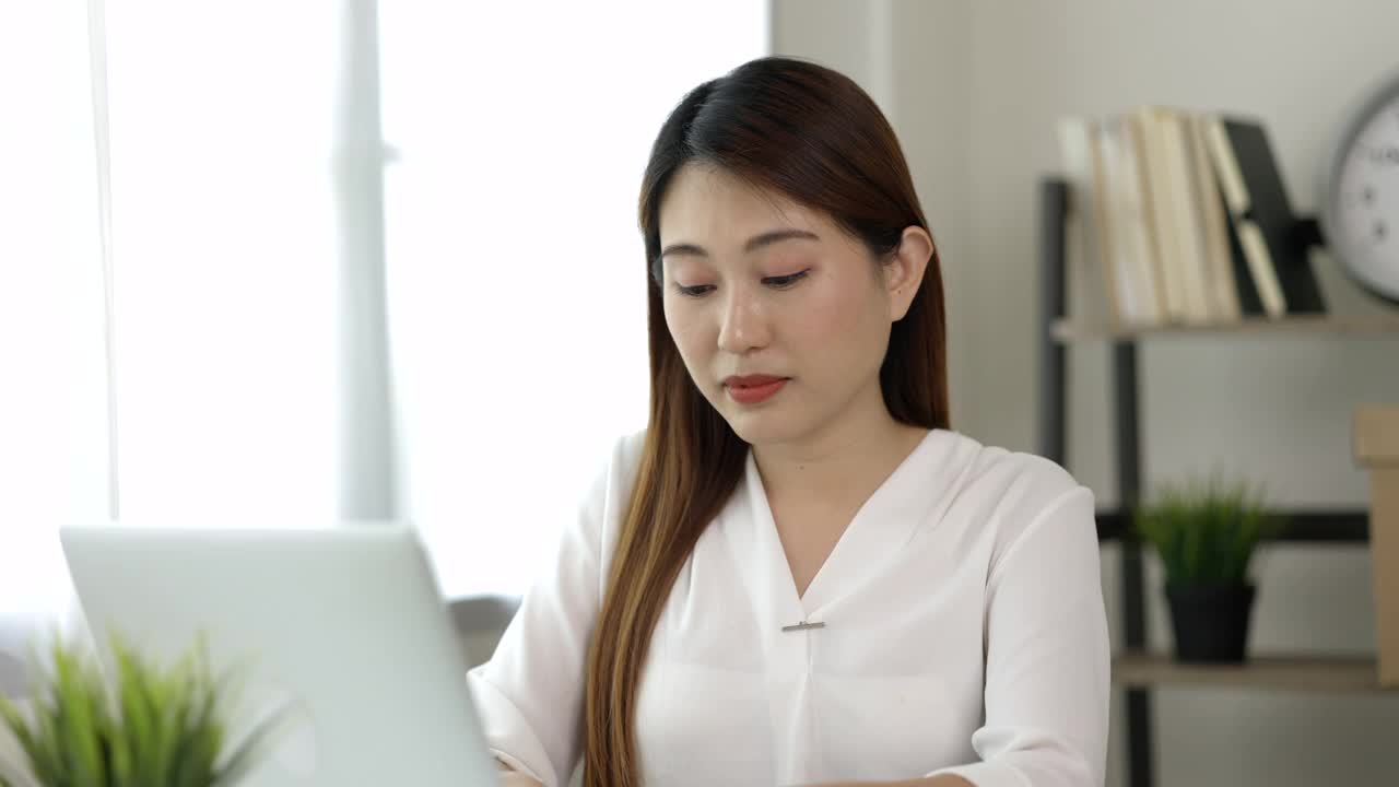 年轻的亚洲商务女性揉她的眼睛，她感到抑郁，压力，头痛，由于长时间使用笔记本电脑而感到疲劳，她出现了办公室综合症。视频素材