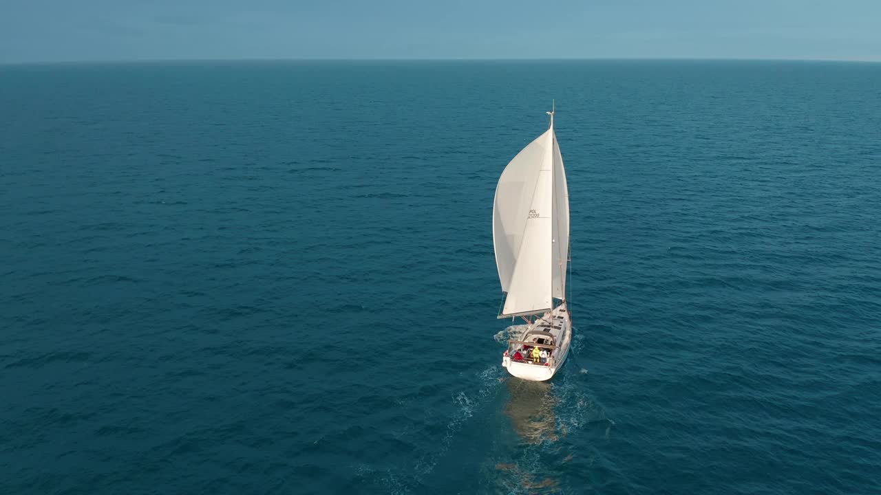 太阳游艇，白色的帆在开阔的海上空中。在夏日阳光明媚的日子里航行海景。在海湾的帆船上驾驶游艇。奢华的生活方式，冷静放松的理念。电影的风景视频素材