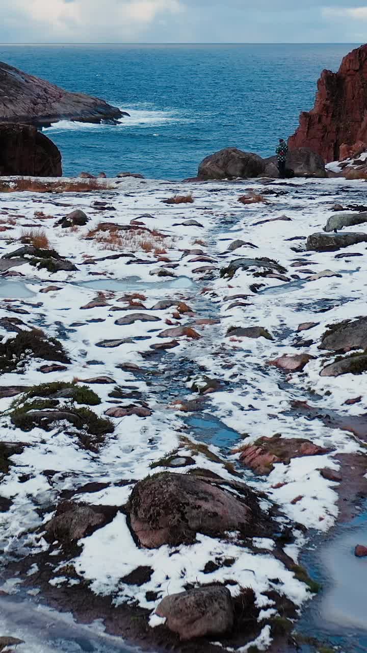 白雪覆盖的岩石海岸和大海的美丽景色。从岸上看视频素材