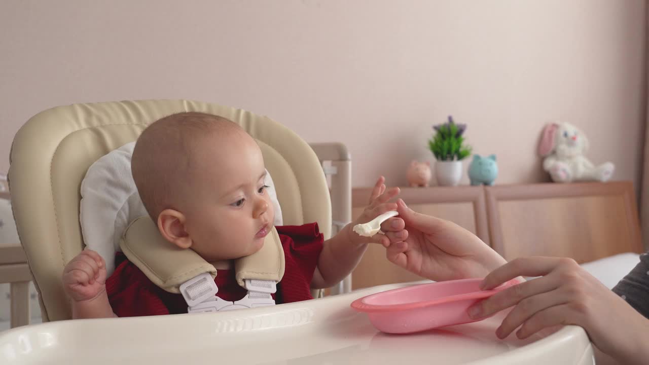 母亲用白软干酪喂她新生的女儿。用勺子给宝宝喂酸奶视频素材