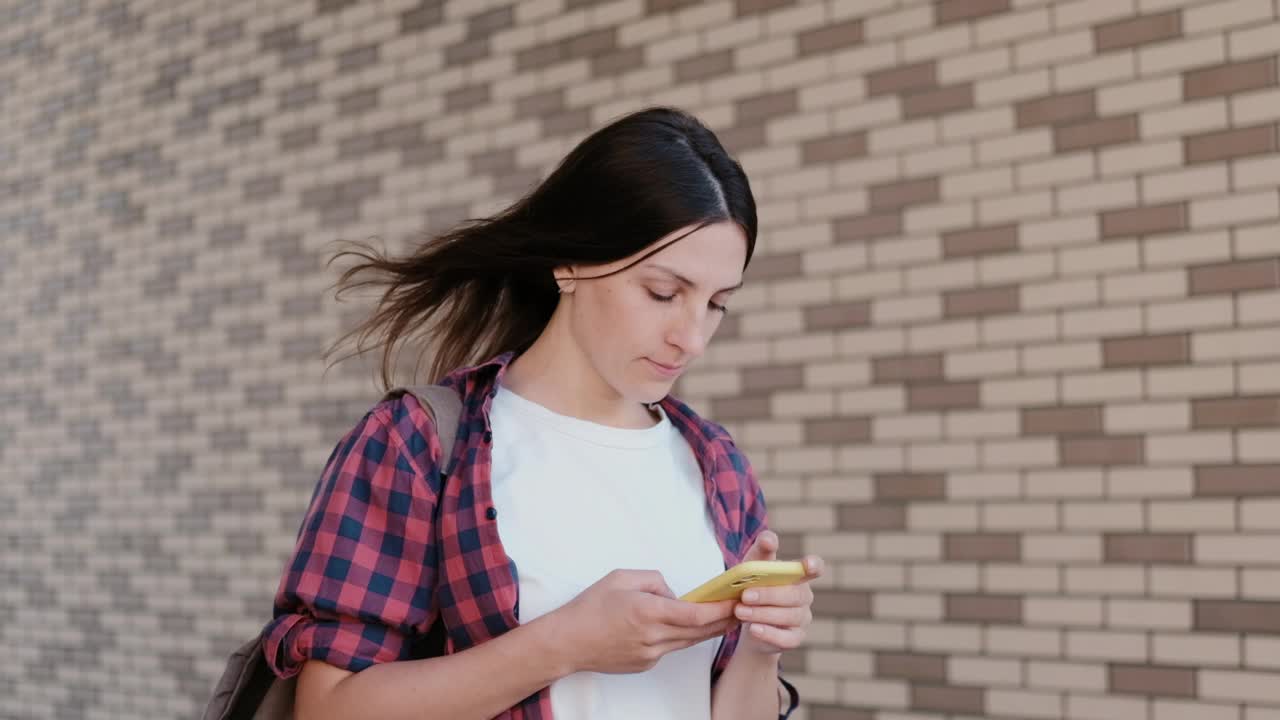 美丽的女孩在户外用智能手机查看社交网络。学生在城市公园休息视频素材