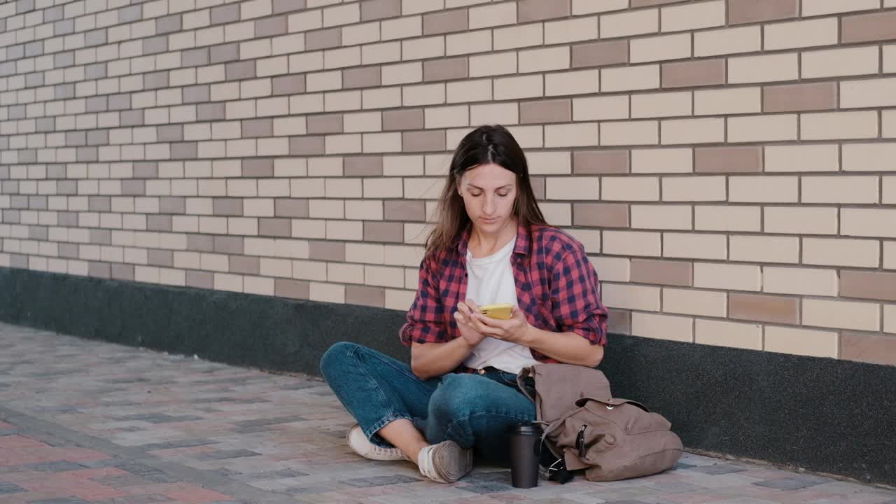 美丽的女孩在户外用智能手机查看社交网络。学生在城市公园休息视频素材