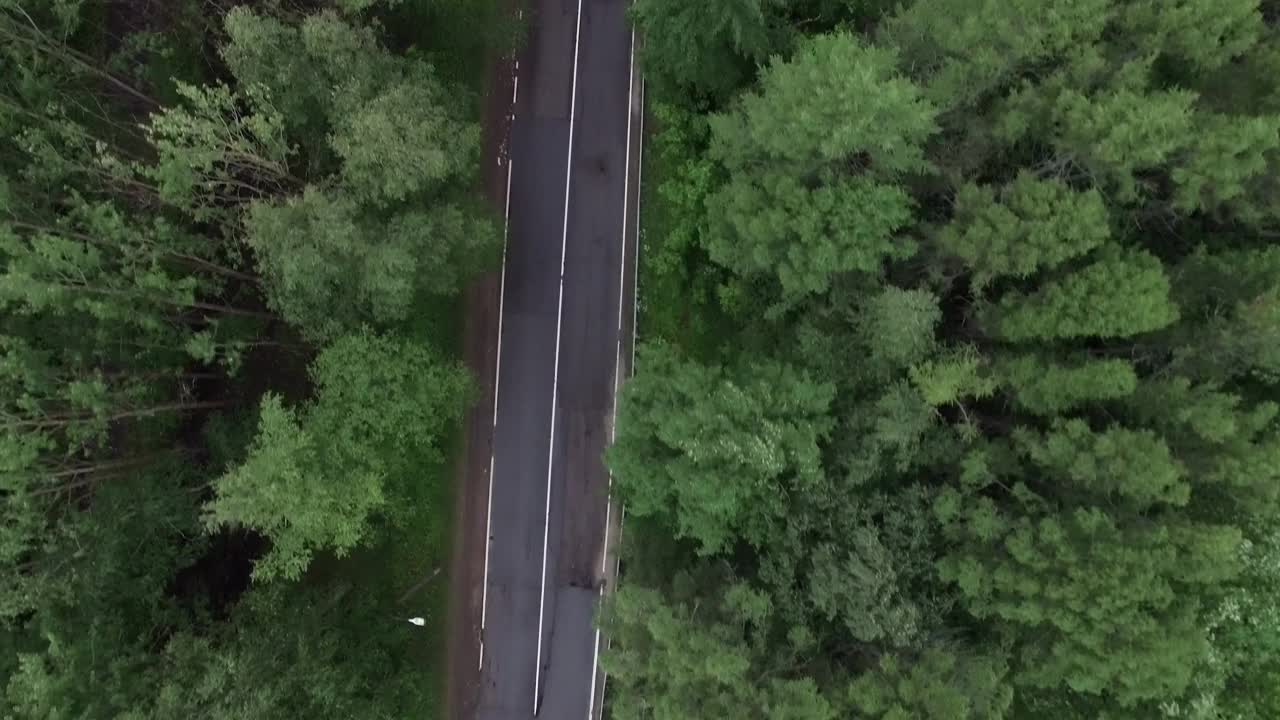 无人机俯视图摄像头跟踪黑色汽车在空旷的高速公路上行驶非常快沿多云的秋天森林大气公路旅行。鸟瞰图。4 k的片段视频下载