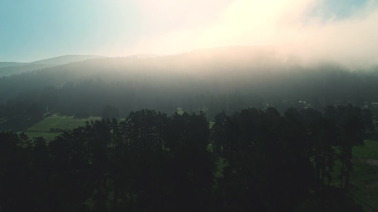 鸟瞰图山地森林和绿色的牧场，晨雾和灿烂的日出，4k视频视频素材