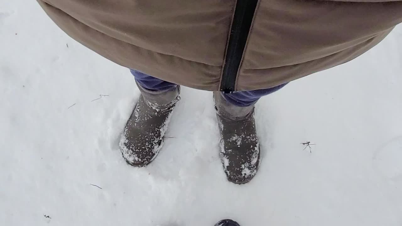 在阳光明媚的冬日，妇女们在雪地里穿靴子。俯视图全高清视频视频素材