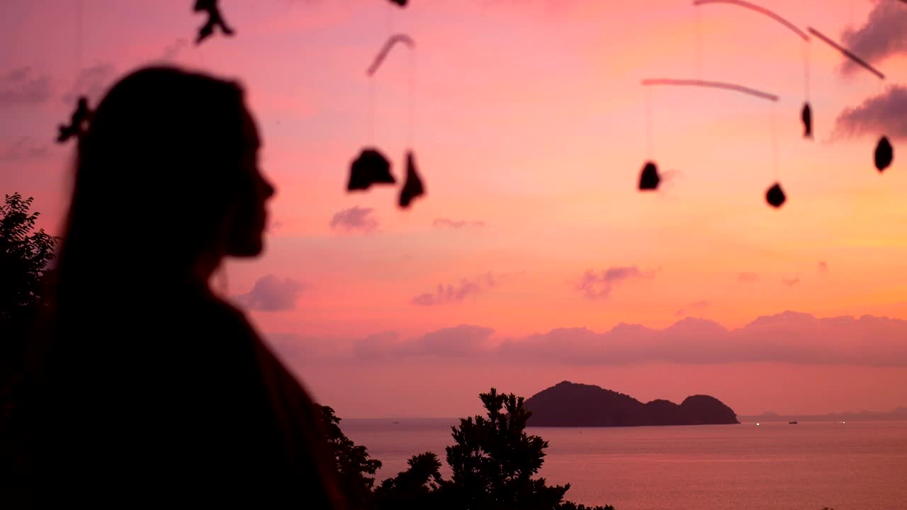 女孩站在日落上欣赏大海和岛屿的景色视频素材