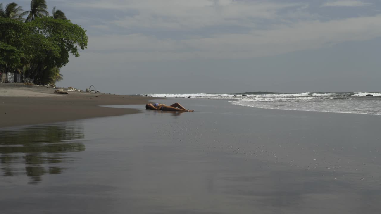 鸟瞰图沿海洋海滩海岸线经过日光浴的女人/圣布拉斯，拉利伯塔德，萨尔瓦多视频素材