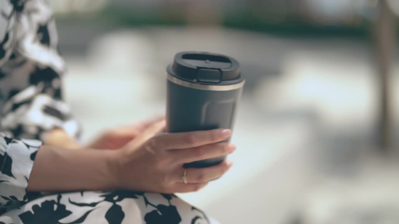 特写亚洲女人用可重复使用的旅行杯喝咖啡。视频素材