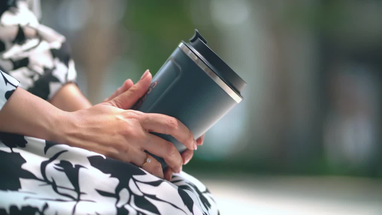 特写亚洲女人用可重复使用的旅行杯喝咖啡。视频素材