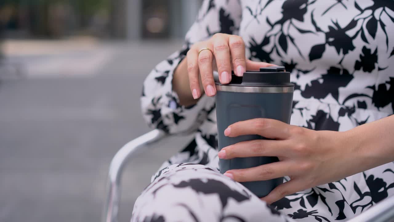 特写亚洲女人用可重复使用的旅行杯喝咖啡。视频素材