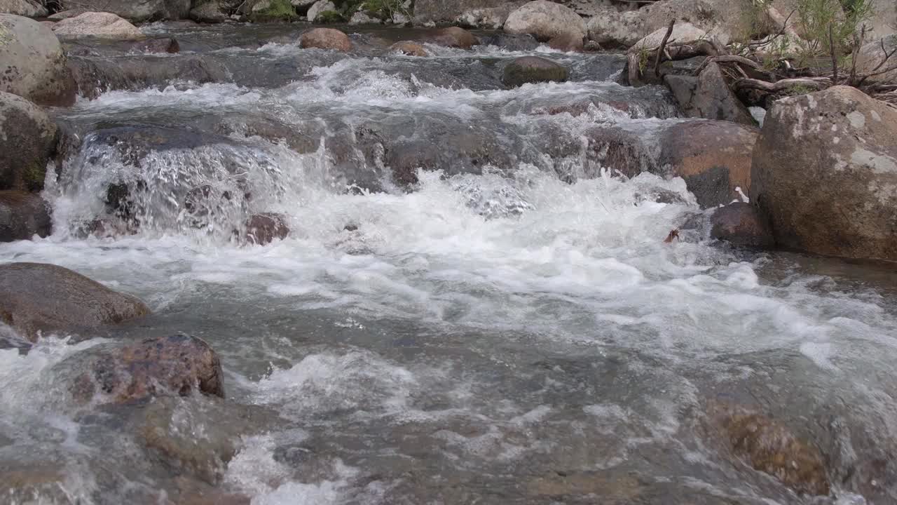 山间的河水从巨石上奔流而下。湍急的水流搅动水流，溅起水花。石质河床。透过透明的表面可以看到花岗岩底部视频素材