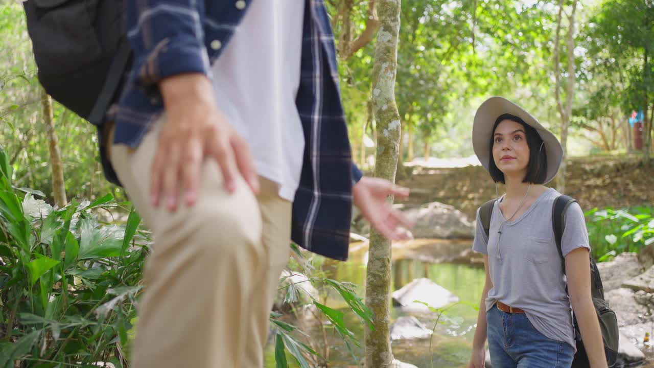 年轻的亚洲夫妇白种人男性和美丽的女性朋友一起在森林旅行旅行。在大自然的野外，那个活跃的男子拉起了那个女孩。他们继续快乐地走着。视频素材