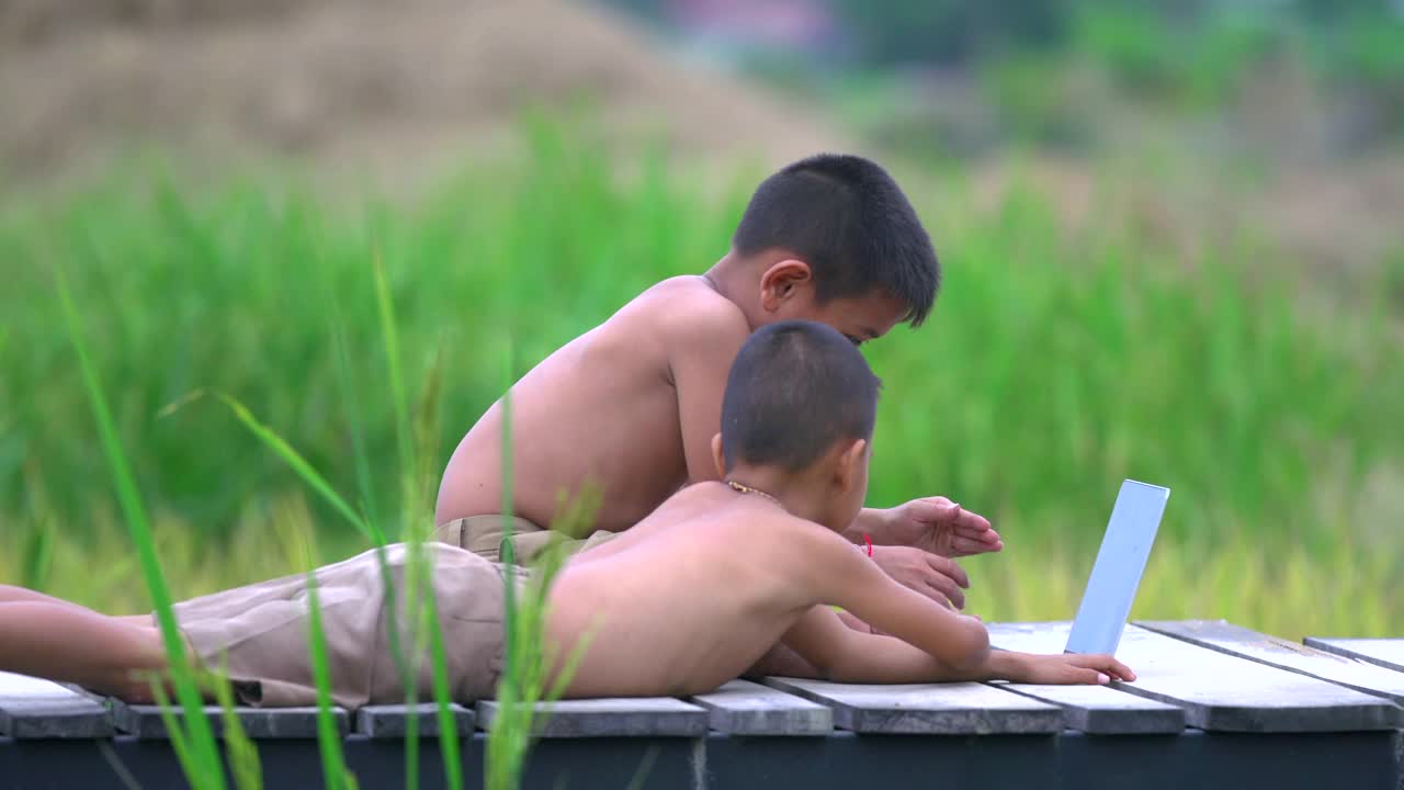 两个农村男孩愉快地玩着笔记本视频素材