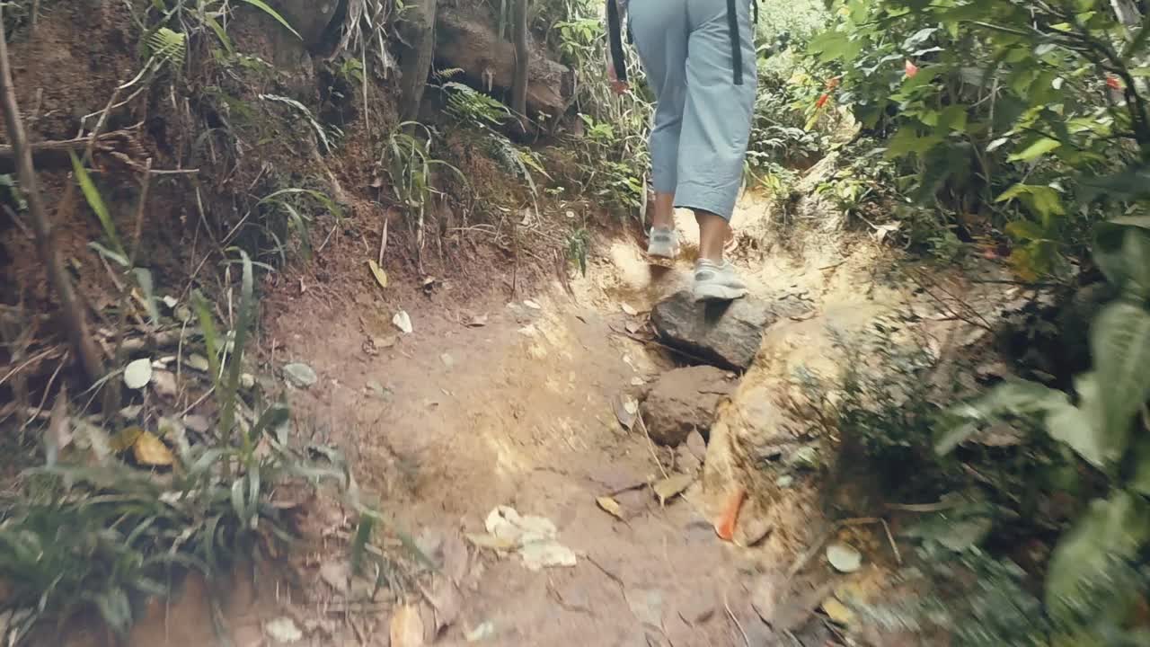 慢镜头近距离观看女子的脚穿着休闲运动鞋走在森林小径上视频素材