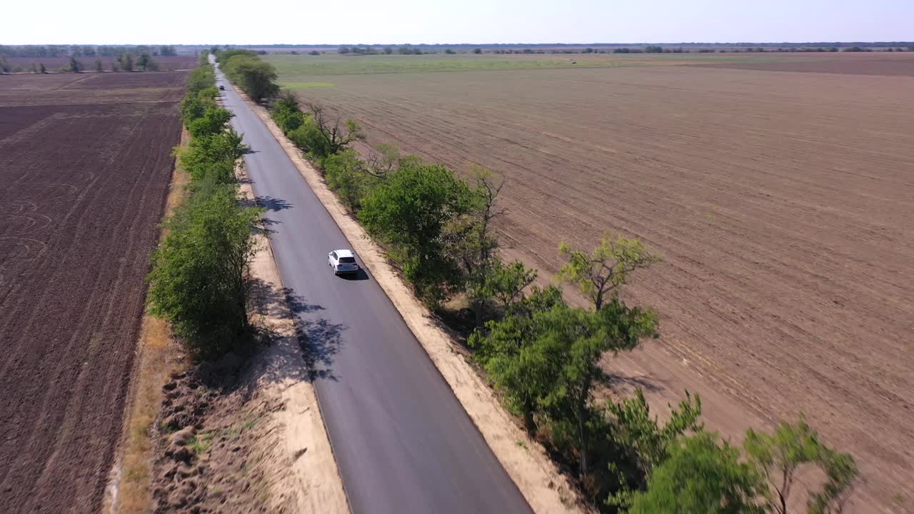 动态航拍画面，一辆白色汽车在乡村道路上移动视频素材