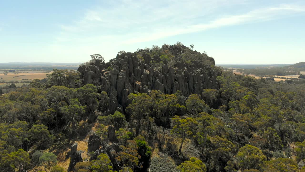 4K空中跟踪飞向澳大利亚Hanging Rock。小的人物站在壮观的岩石上。视频素材