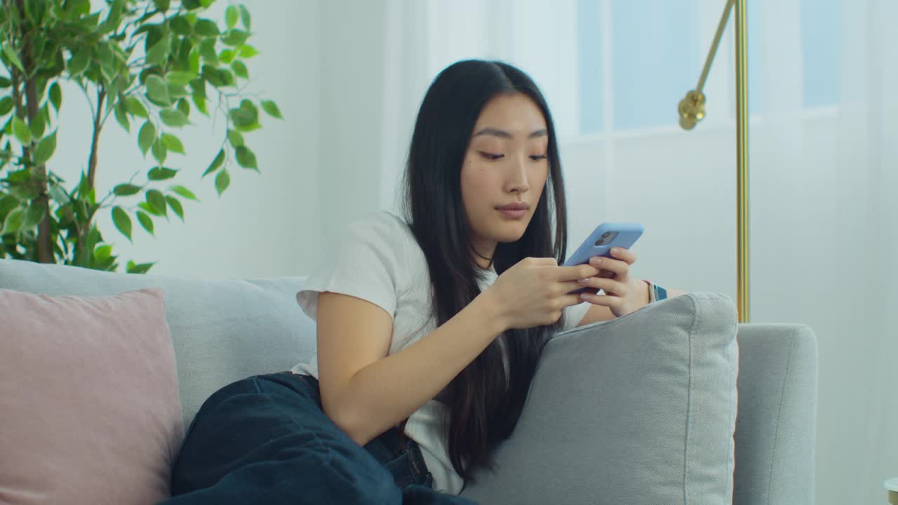 亚洲女孩正在手机上激活虚拟助手。年轻的混血女性在社交网络上为朋友或在家里使用智能手机录制语音信息。视频素材