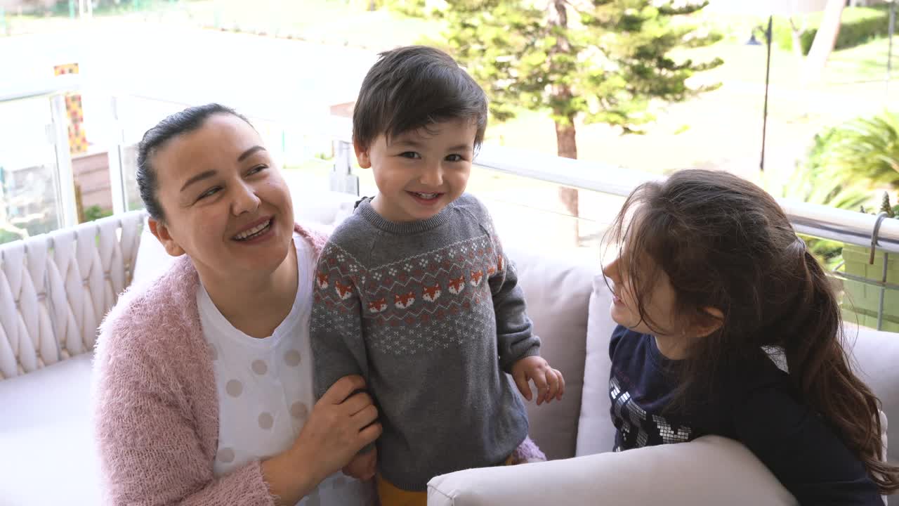 孩子们亲吻妈妈，在家里的阳台上欢呼视频素材